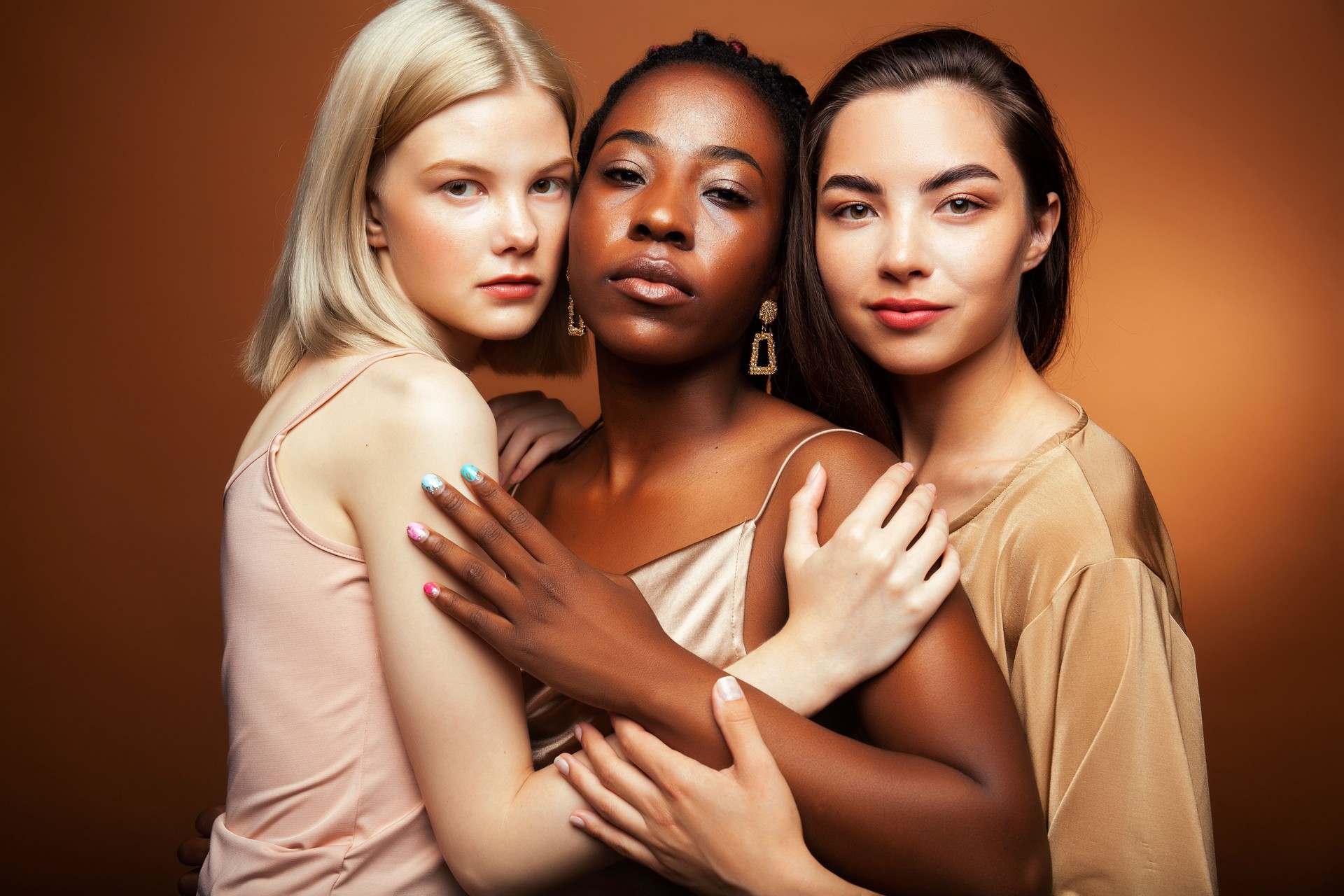young pretty asian, caucasian, afro woman posing cheerful together on brown background, lifestyle diverse nationality people concept