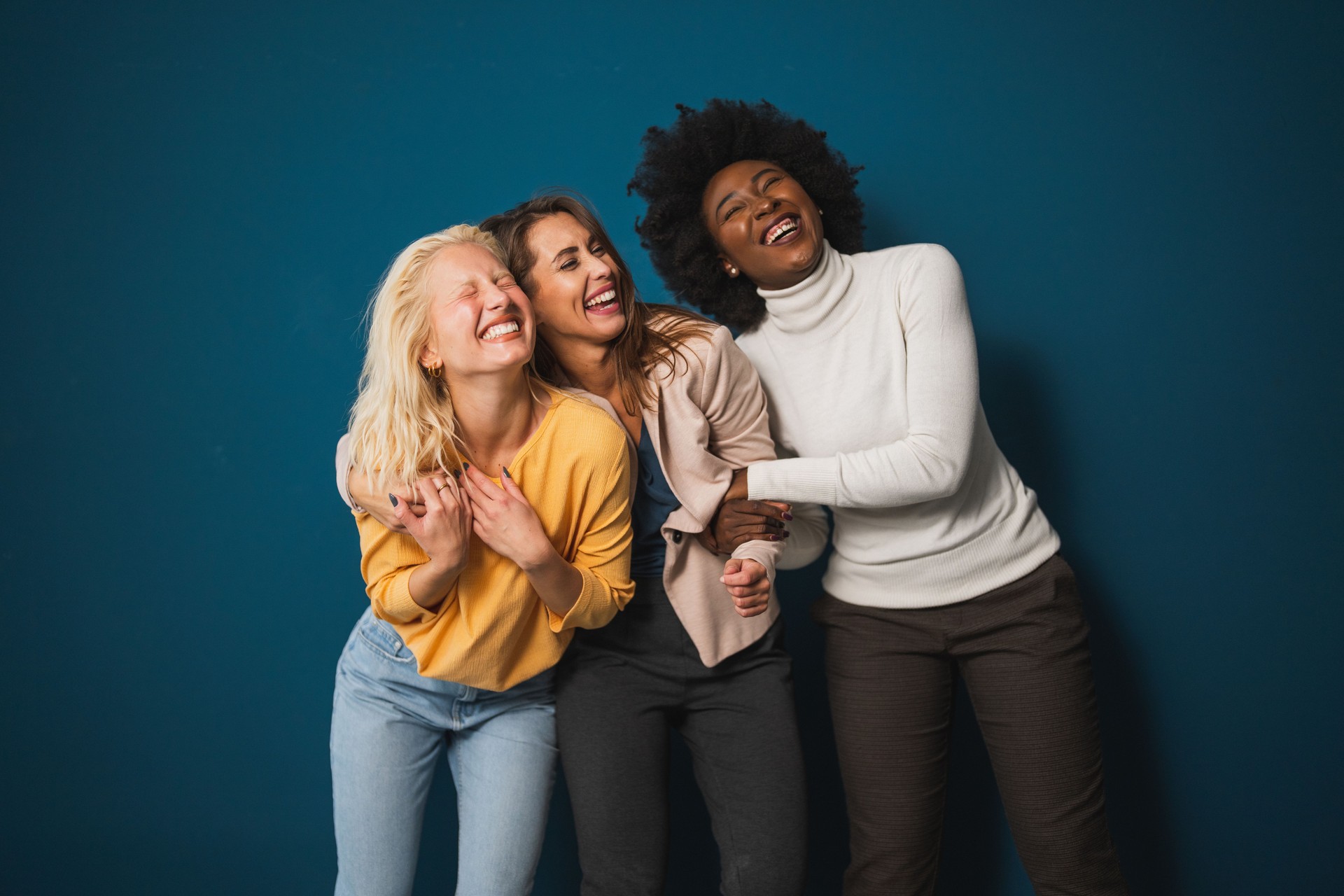 Multicultural female friends smiling and embracing each other in a studio